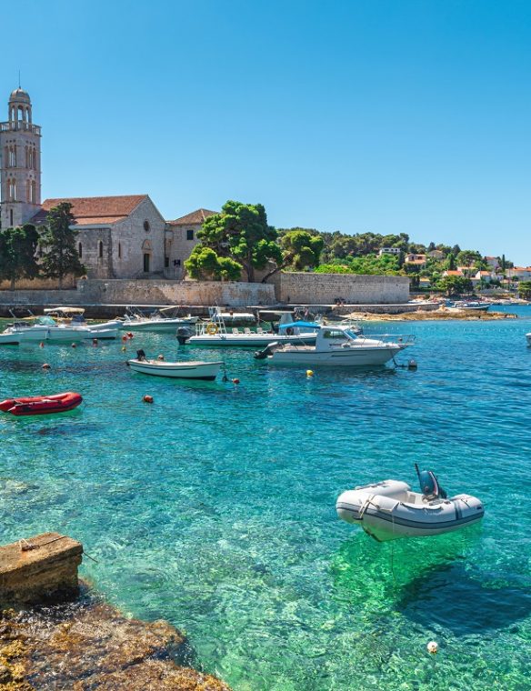 Turquoise water of Adriatic sea bay on Hvar island with franciscian monastery and boats in Dalmatia region, Croatia