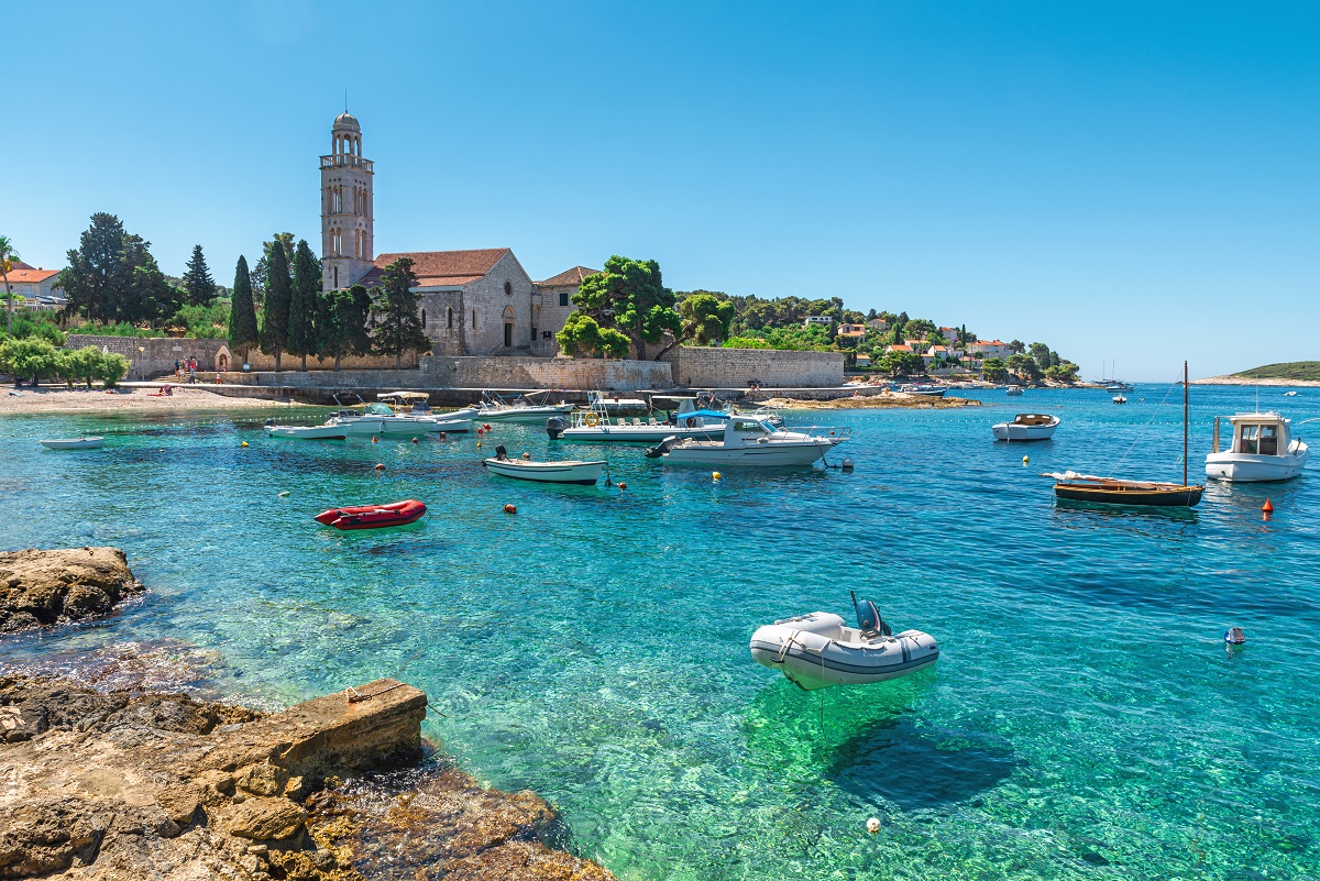 Turquoise water of Adriatic sea bay on Hvar island with franciscian monastery and boats in Dalmatia region, Croatia